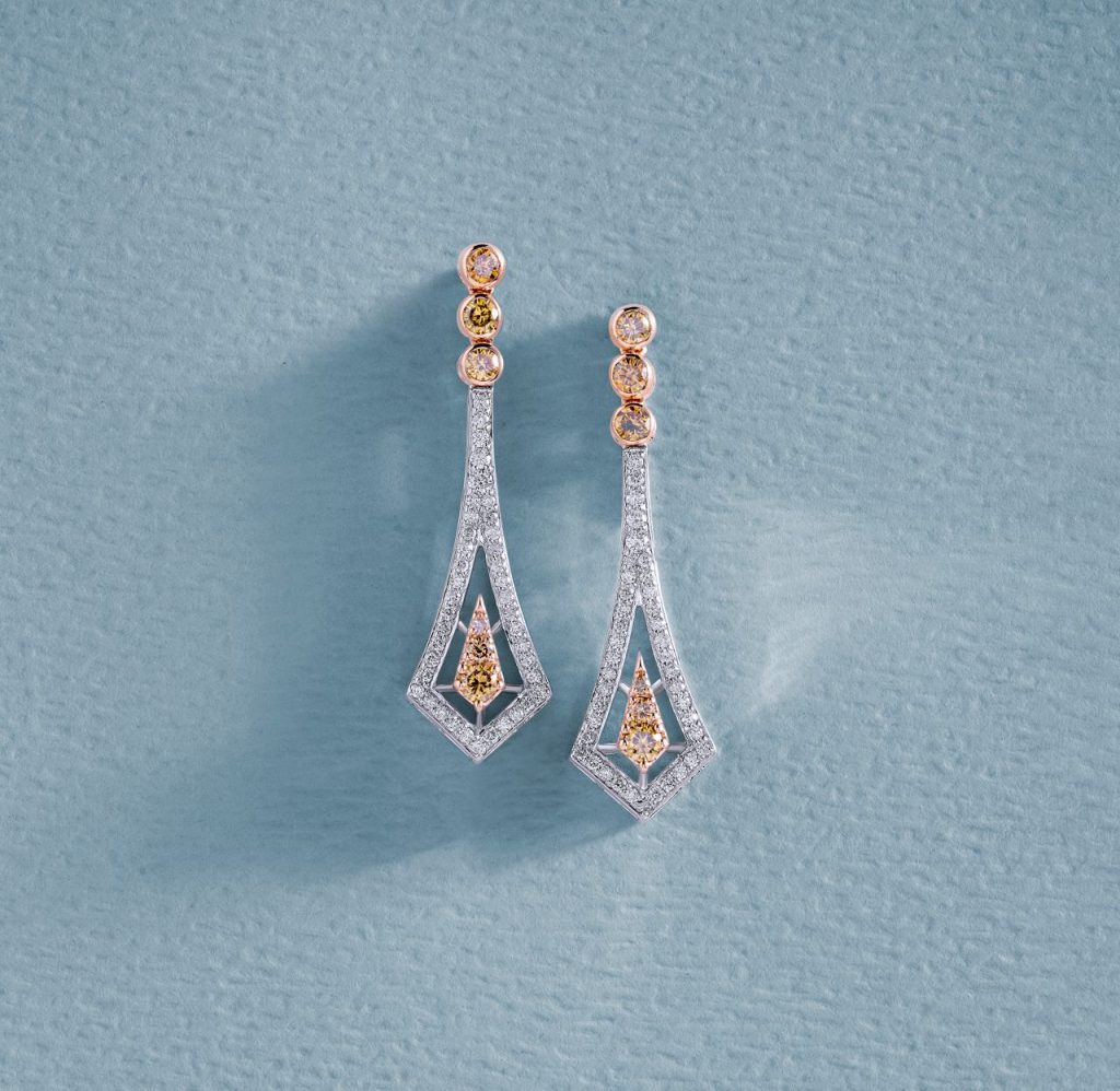 Beautiful diamond earrings displayed on a baby blue textured surface, highlighting luxury and elegance.