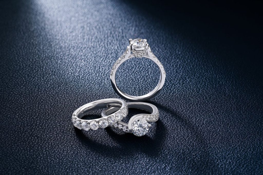 Close-up of luxurious diamond engagement and wedding rings on a textured surface, showcasing elegance and craftsmanship.